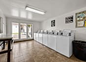 Thumbnail 38 of 39 - A laundromat with a row of washers and dryers.