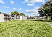 Thumbnail 23 of 39 - A grassy field with apartment buildings in the background.