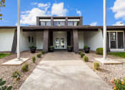Thumbnail 19 of 39 - the front of a building with two pillars and a concrete walkway