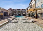 Thumbnail 20 of 24 - A fountain in the middle of a pool surrounded by lounge chairs.