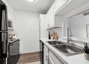 Thumbnail 6 of 35 - A modern kitchen with a black refrigerator and stainless steel sink.