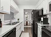 Thumbnail 5 of 35 - A modern kitchen with black appliances and white cabinets.