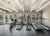 Thumbnail 22 of 35 - A spacious gym with treadmills, elliptical machines, and stationary bikes.