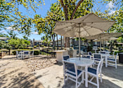 Thumbnail 19 of 35 - A patio with white chairs and tables under umbrellas.