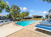 Thumbnail 16 of 35 - A pool surrounded by sun loungers and trees.