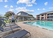 Thumbnail 11 of 18 - A pool area with lounge chairs and a building in the background.