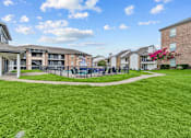 Thumbnail 13 of 18 - A grassy area in front of apartment buildings with a pink flowering bush.
