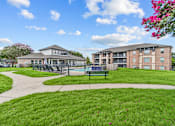 Thumbnail 14 of 18 - A grassy area with a building and a fence in the background.