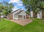 Thumbnail 15 of 18 - A house with a grey roof and a stone chimney is surrounded by a green lawn.
