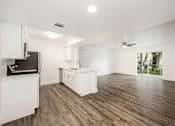 Thumbnail 29 of 42 - an empty living room with a kitchen and a ceiling fan
