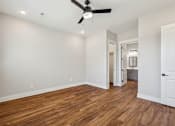 Thumbnail 22 of 38 - A room with a ceiling fan and wooden floors.