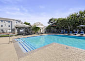 Thumbnail 8 of 14 - A swimming pool with a slide and a building in the background.