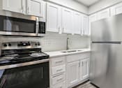 Thumbnail 10 of 17 - A modern kitchen with white cabinets and stainless steel appliances.