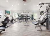 Thumbnail 25 of 29 - a gym with cardio equipment and weights on a wooden floor