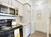 Thumbnail 9 of 40 - A kitchen with a stove, microwave, and refrigerator.