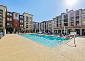 Thumbnail 1 of 38 - A sunny day at a pool in front of apartment buildings.