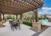 Thumbnail 16 of 17 - a covered patio with a table and chairs and a pool in the background