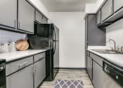 Thumbnail 16 of 40 - an empty kitchen with white counters and black appliances and a black refrigerator