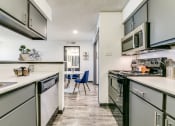 Thumbnail 17 of 40 - a kitchen with white cabinets and appliances and a dining room with a table