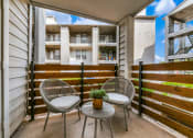 Thumbnail 26 of 40 - a patio with two chairs and a table in front of a fence