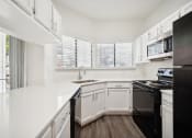 Thumbnail 2 of 33 - a renovated kitchen with white cabinets and black appliances