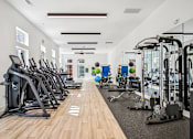 Thumbnail 27 of 39 - A gym with a variety of exercise equipment including treadmills, stationary bikes, and weight machines.