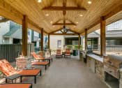 Thumbnail 20 of 30 - a covered patio with a grill and tables and chairs