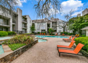 Thumbnail 24 of 29 - a swimming pool with orange chairs in front of an apartment building