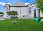 Thumbnail 26 of 29 - an apartment building with a yard with a dog statue and a ping pong table