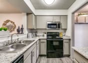 Thumbnail 1 of 29 - a kitchen with white cabinets and black appliances and granite counter tops