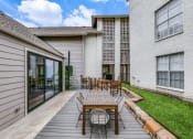 Thumbnail 21 of 29 - a patio with a wooden table and chairs in front of a building