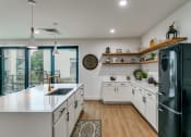 Thumbnail 15 of 29 - a kitchen with white cabinets and black appliances and a sliding glass door to a balcony