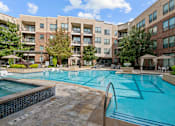 Thumbnail 23 of 33 - a swimming pool with an apartment building in the background
