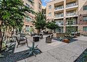 Thumbnail 27 of 33 - a courtyard with a seating area and trees in front of an apartment building