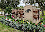 Thumbnail 32 of 33 - a brick sign with a black horse on it next to a flower garden