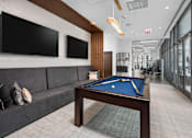 Thumbnail 21 of 25 - A pool table in a room with a couch and two TVs.