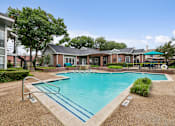 Thumbnail 17 of 42 - A swimming pool surrounded by a fence and a building in the background.