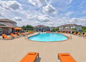 Thumbnail 16 of 20 - A large swimming pool surrounded by orange lounge chairs.