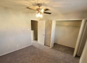 Thumbnail 24 of 36 - an empty living room with a ceiling fan and empty closets