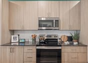 Thumbnail 3 of 30 - a kitchen with wooden cabinets and a stove and a microwave