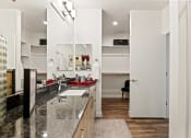 Thumbnail 12 of 30 - a kitchen with granite countertops and a sink and a door to a living room