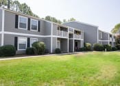 Thumbnail 13 of 36 - a gray apartment building with a grassy yard