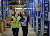 Thumbnail 43 of 45 - A man and a woman are walking in a warehouse.