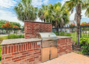 Thumbnail 35 of 39 - a brick outdoor kitchen with a grill and palm trees