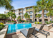 Thumbnail 29 of 42 - A pool surrounded by palm trees and lounge chairs.