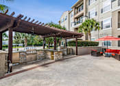 Thumbnail 34 of 42 - A patio area with a wooden pergola and a stone wall.