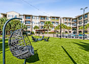 Thumbnail 36 of 42 - A park with a swing set and apartment buildings in the background.