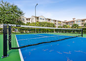 Thumbnail 39 of 42 - A tennis court with a net and a green and blue surface.