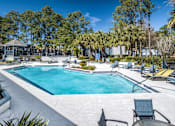 Thumbnail 4 of 35 - A swimming pool surrounded by trees and chairs.