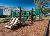 Thumbnail 30 of 35 - A playground with a green swing set and a slide.